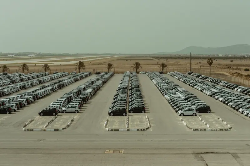 Rows of small unbranded hire cars in numbered bays on an open-air rental lot near Palma airport.